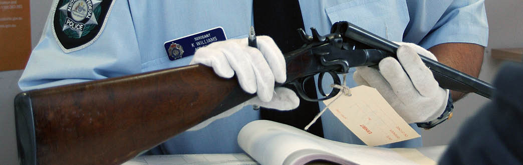 A uniformed police office holder a firearm with a label tagged on it.