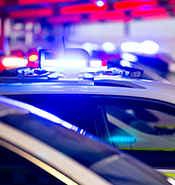 Top of a line of police cars with their lights flashing sending a red and blue hue to the blurred out background.