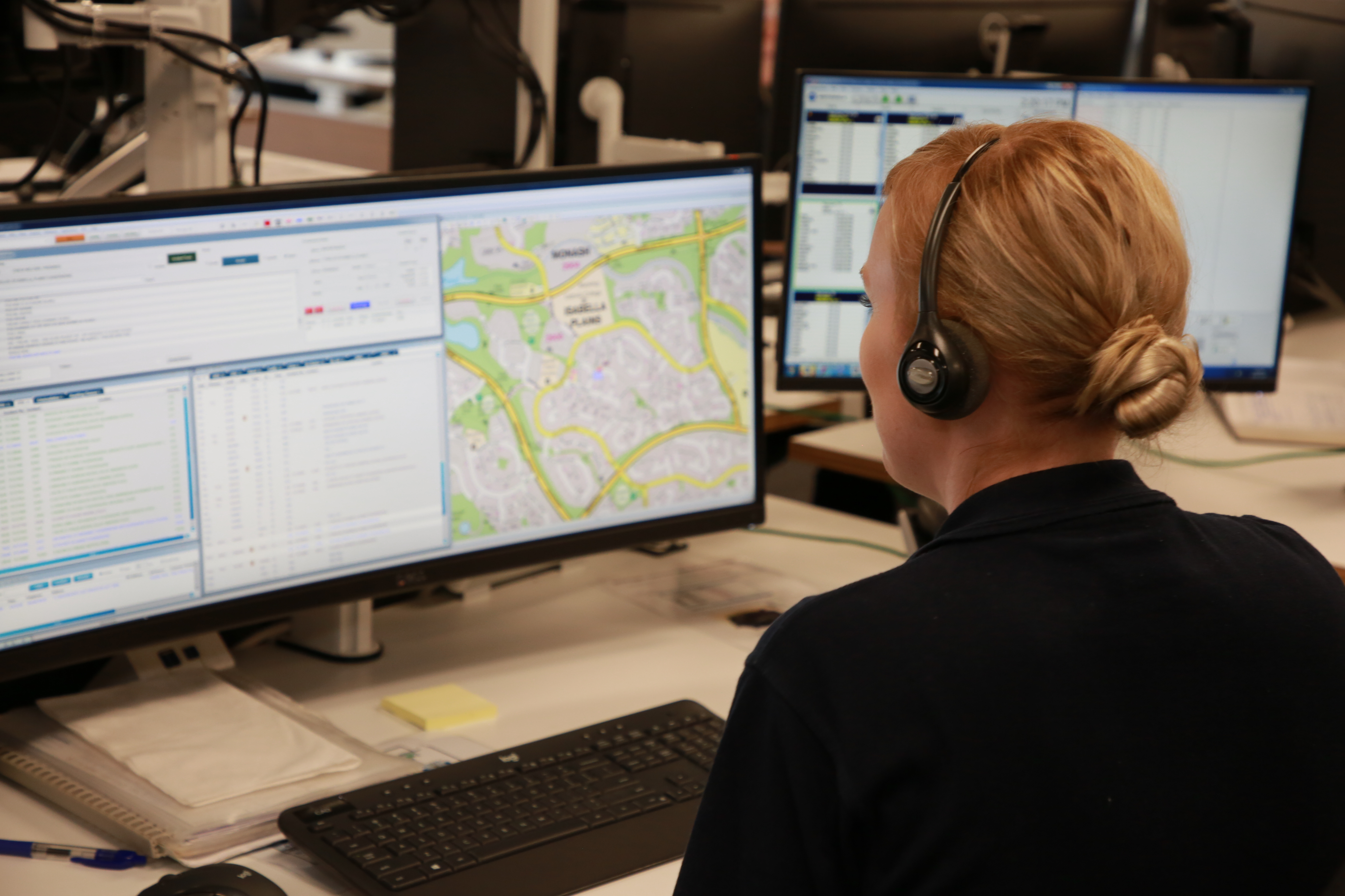 A female call centre operator sitting in an office taking a call on her headset.