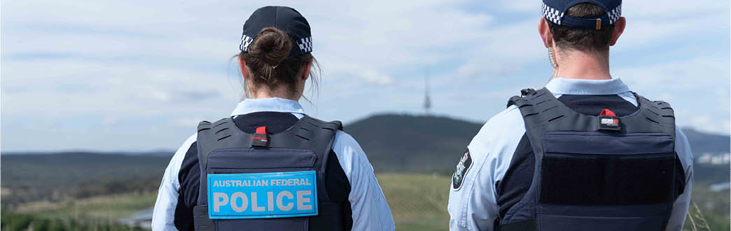 Two police officers in uniform looking out at Black Mountain Tower in Canberra 