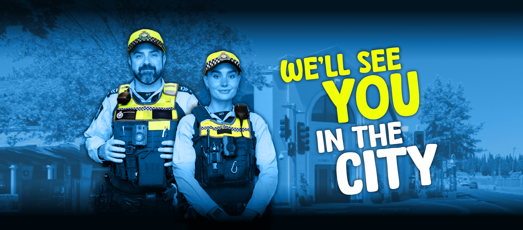 Two police officers, a male and a female, stand in front of the Canberra CBD with the words "We'll see you in the city".