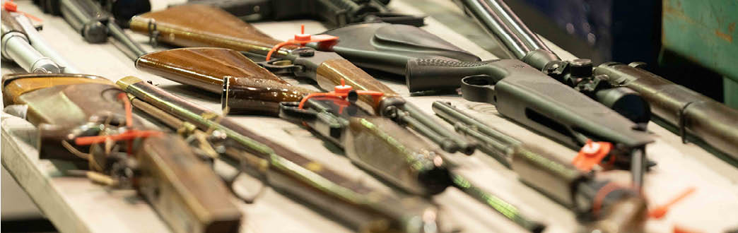 Multiple brown and black guns on a table 