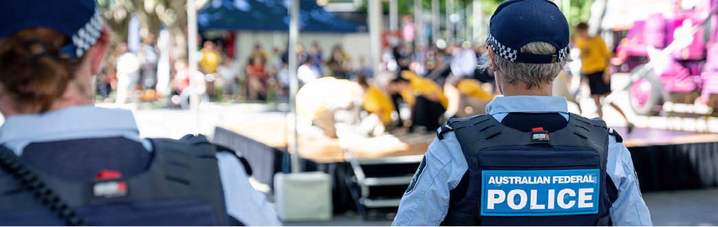 Two police officers in uniform looking at an event crowd