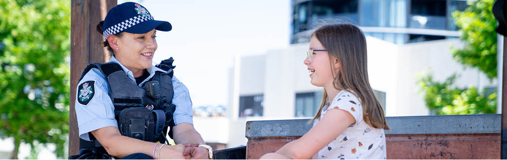 A woman police officer in uniform talking to a young girl 