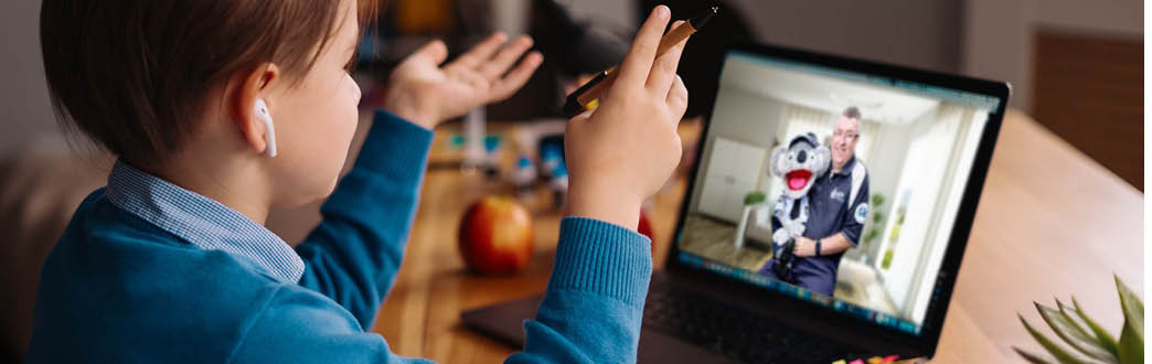 A young child watching a laptop screen with constable kenny koala on the screen