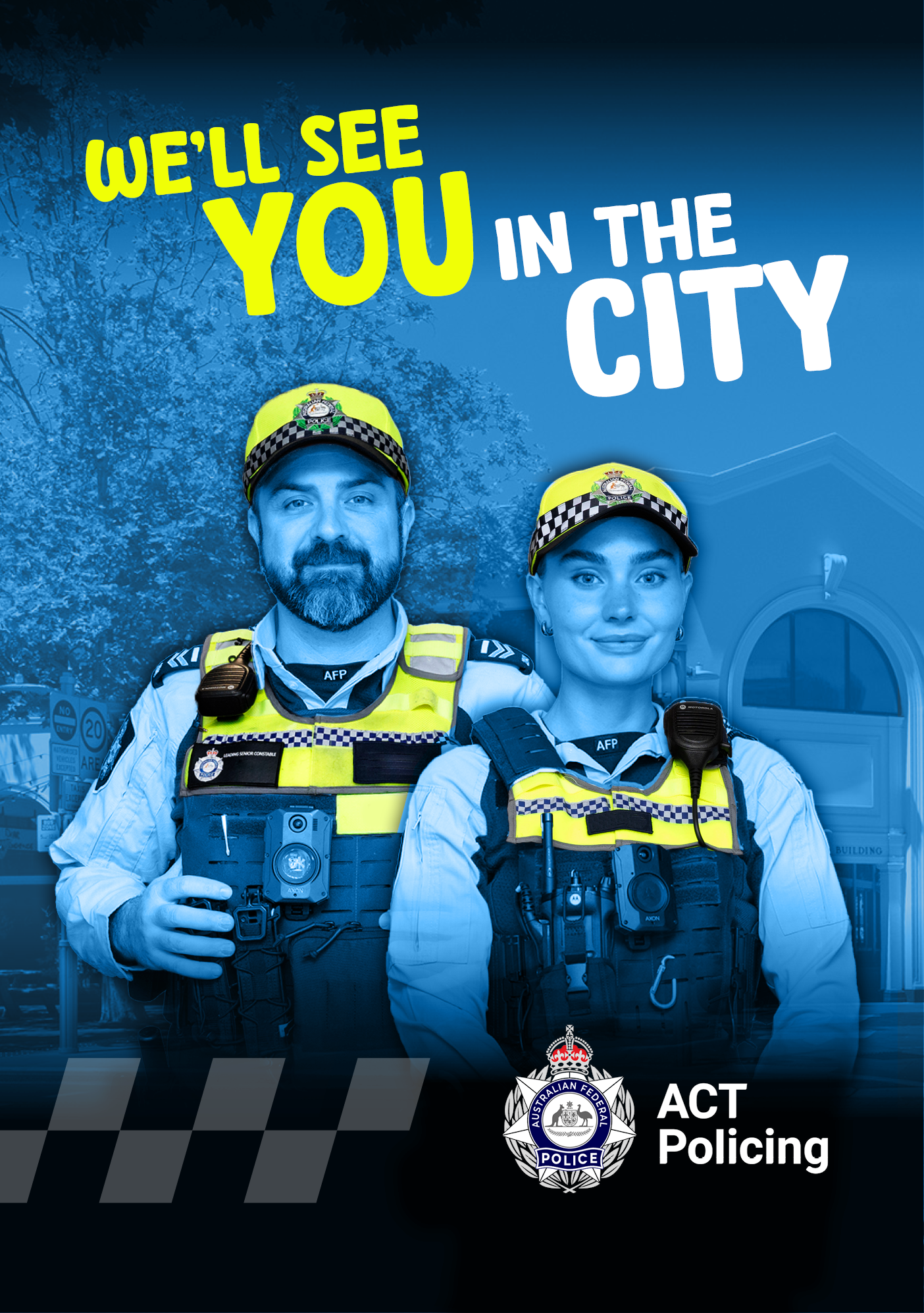 Two police officers, a male and a female, standing in front of the Canberra CBD with the words 